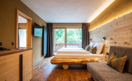 Schlafzimmer mit Holzmöbeln, großem Bett, Sofa und Balkonblick